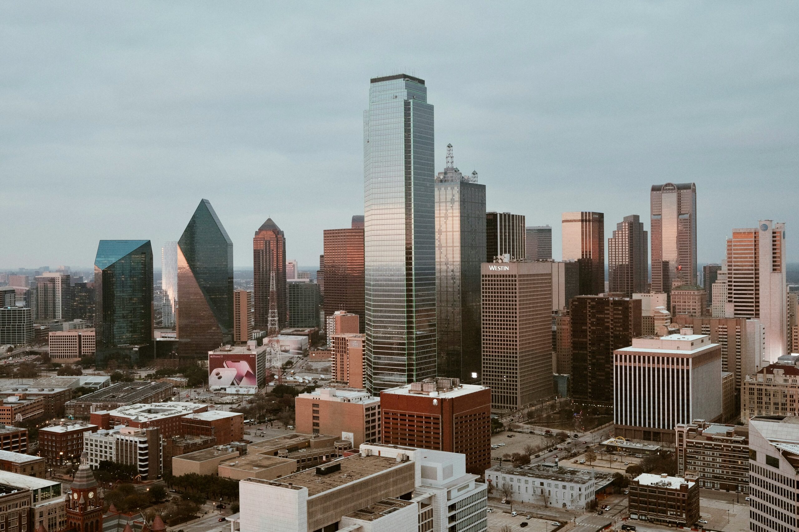 Downtown Dallas skyline at dusk, featuring a mix of high-rises and low residential buildings